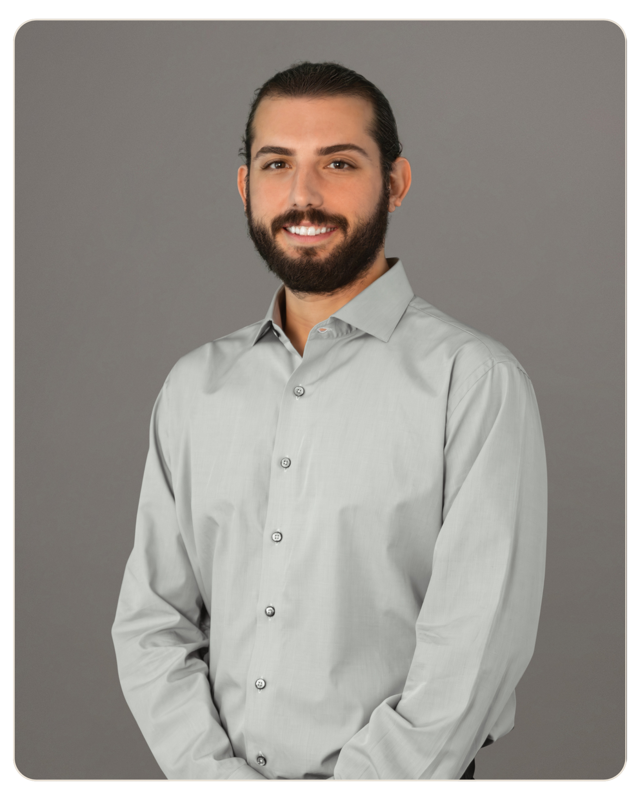 Flyland - Trost - Robert Mazo Smiling man with dark hair and beard in a light grey button-down shirt, neutral backdrop.